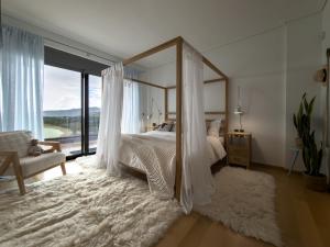 a bedroom with a canopy bed with a large window at Astraea Villa in Karistos +83 photos