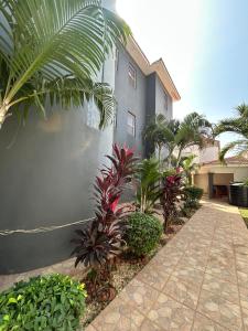 a building with plants and a sidewalk in front of it at Fawis Lodge in Brusubi