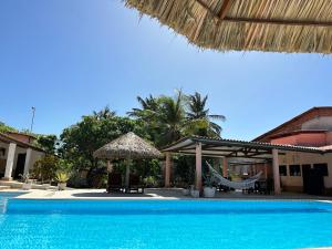 a swimming pool with a hammock and an umbrella at Pousada em Paracuru Casa Eco Kite Surf & Relax in Paracuru