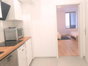 a kitchen with white cabinets and a microwave at Chez Alice 1 in Montbéliard +28 photos