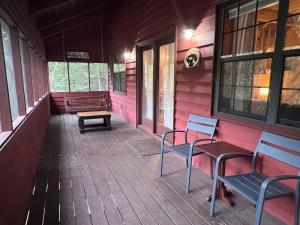a porch of a house with two chairs and a bench at Bigfoots River Retreat in Mineral Bluff