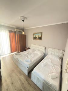two beds in a hotel room with white sheets at Alfas Beach Apartments in Shëngjin