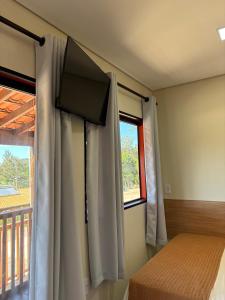 a bedroom with a flat screen tv on the wall at Pousada Pitauá in Socorro