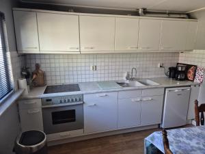 a kitchen with white cabinets and a stove and a sink at Molenzicht in Elspeet +6 photos