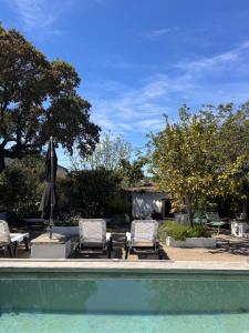 a swimming pool with two chairs and an umbrella at Casa Melissa in Santo António do Baldio