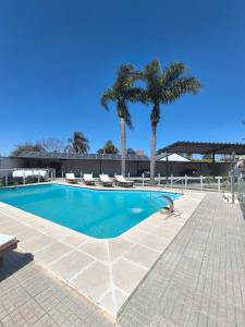 a swimming pool with two palm trees and a building at HOTEL MIRAMAR in Miramar