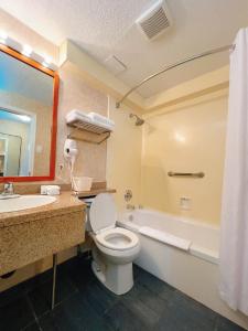 a bathroom with a toilet and a sink and a tub at North Vancouver Hotel in North Vancouver