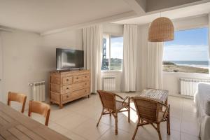 a living room with a television and a table and chairs at Cariló Forest in Carilo