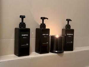 three bottles of soap and a candle on a shelf at Rifugio a due passi dal mare in Rimini