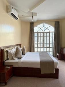 a bedroom with a large bed with a window at Deluxe Apartment in Muscat +15 photos