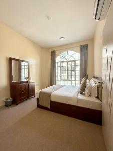 a bedroom with a large bed and a window at Deluxe Apartment in Muscat