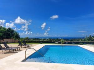 a swimming pool with two lounge chairs and a blue sky at Ocean View Villa with pool in Christ Church