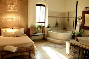 a bedroom with a bed and a tub and a sink at Sunny's Suite in Safed