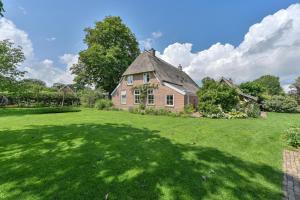 an old brick house with a large grass yard at B&B De Emmer in Noord-Sleen