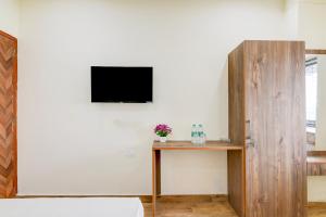 a room with a table and a television on a wall at Hotel O B&B Guest House in kolkata