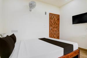 a bedroom with a bed and a tv and a door at Hotel O B&B Guest House in kolkata