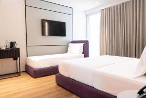 a hotel room with two beds and a tv at Mango Luxury Resorts in Sarandë