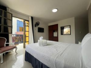 a bedroom with a white bed and a balcony at Hotel Suite Santa Rosa in Santa Rosa de Cabal