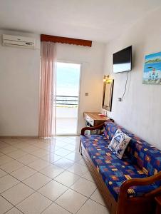 a living room with a couch and a television at Studios Maria in Chrysi Ammoudia