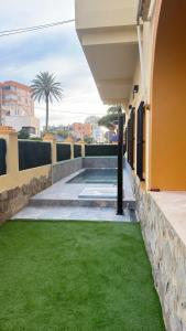 a backyard with green grass next to a building at El Chalecito De Alicante in El Campello
