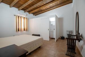 a bedroom with a bed and a table and a bathroom at Casa dos Avós in Mértola
