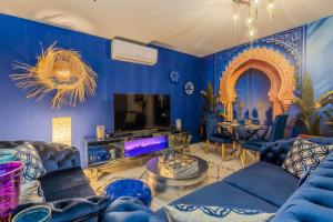 a blue living room with blue furniture and a tv at Suite Riad Luxe avec jacuzzi proche Disney in Nanteuil-lès-Meaux