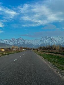 an empty road with snow capped mountains in the distance at Mountain View Guest House in Zhabagly