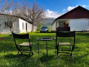two chairs and a table and a car in a yard at Mountain View Guest House in Zhabagly