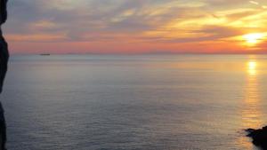 a sunset over the water with a boat in the distance at il mare stone house with Aegean view in Agios Dimitrios +31 photos