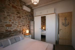 a bedroom with a bed and a stone wall at il mare stone house with Aegean view in Agios Dimitrios