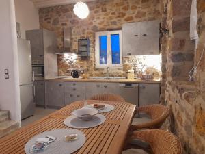 a kitchen with a wooden table with chairs and a tableasteryasteryasteryasteryastery at il mare stone house with Aegean view in Agios Dimitrios