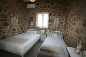 two beds in a room with a brick wall at il mare stone house with Aegean view in Agios Dimitrios