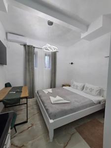 a white bedroom with a large bed and a table at Fabian Studio in Tulcea