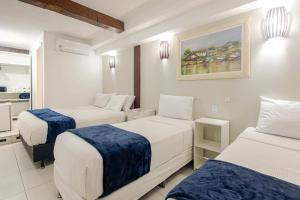 a hotel room with two beds and a bathroom at Pousada Ilha Branca Centro in Búzios