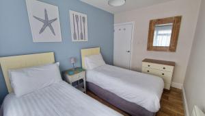 a bedroom with two beds and a night stand with a lamp at 3 The Burrows in Braunton