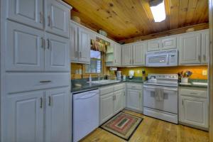 a white kitchen with white appliances and a wooden ceiling at RendezView in Morganton