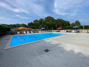 a large swimming pool with chairs and umbrellas at MOBIL-HOME "B27" tout confort avec piscine & lave-linge gratuits in Mimizan