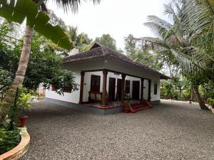 a small house in a garden with palm trees at Writer's Inn in Vaikom