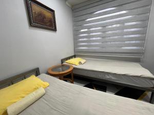 two twin beds in a room with a window at Downtown Homestay in Bishkek +21 photos