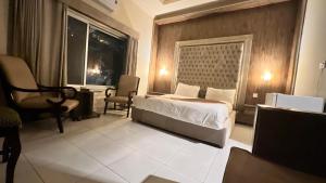 a bedroom with a bed and a chair and a window at Adams Lodge F-7 in Islamabad