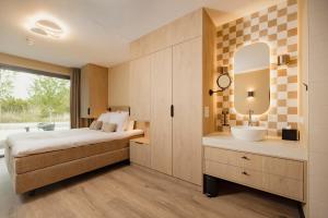 a bedroom with a bed and a sink and a mirror at Hotel Riet I Kloeg Collection in Koudekerke