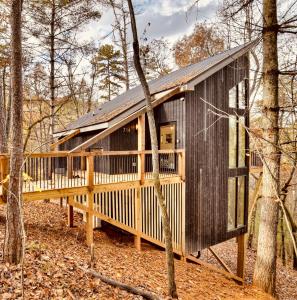 a house with a large deck in the woods at Treeangle Treehouse in Morganton