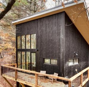 a black house with a wooden deck at Treeangle Treehouse in Morganton