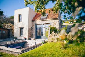 a stone house with a blue door and a yard at L'Envol - Jacuzzi, Sauna et belle vue in Cherbourg en Cotentin