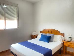 a bedroom with a bed with blue pillows and a window at Hotel Restaurante Costas - Fortuna in Fortuna