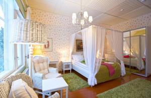 a bedroom with a canopy bed and a chair at Woikoski Feeling - Kirjokiven Kartano in Joutsenlahti