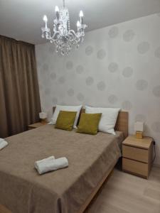 a bedroom with a large bed with a chandelier at GalériusPrémium6 in Siófok