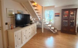 a living room with a flat screen tv on a dresser at Nýlenda - Charming Two Bedroom Seaside Property, Mountain and Town Views in Seyðisfjörður