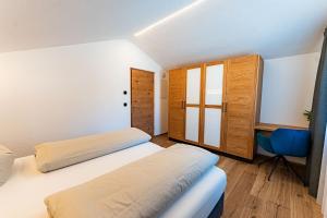 a bedroom with two beds and a blue chair at AurAlpin Apartments in Cadipietra