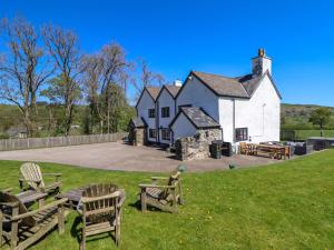 a large white building with wooden chairs in the grass at Cefn Nannau in Corwen